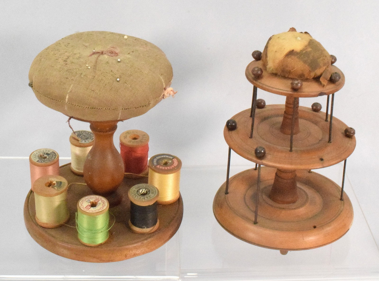 TWO SHAKER ROUND SEWING CARRIERS: Two shaker round sewing carriers, wooden sewing holder and pin cushion, yellow wash surface, with 7 different colored sews, measures 7 " x 6 ", the second one has two levels but doesn't have