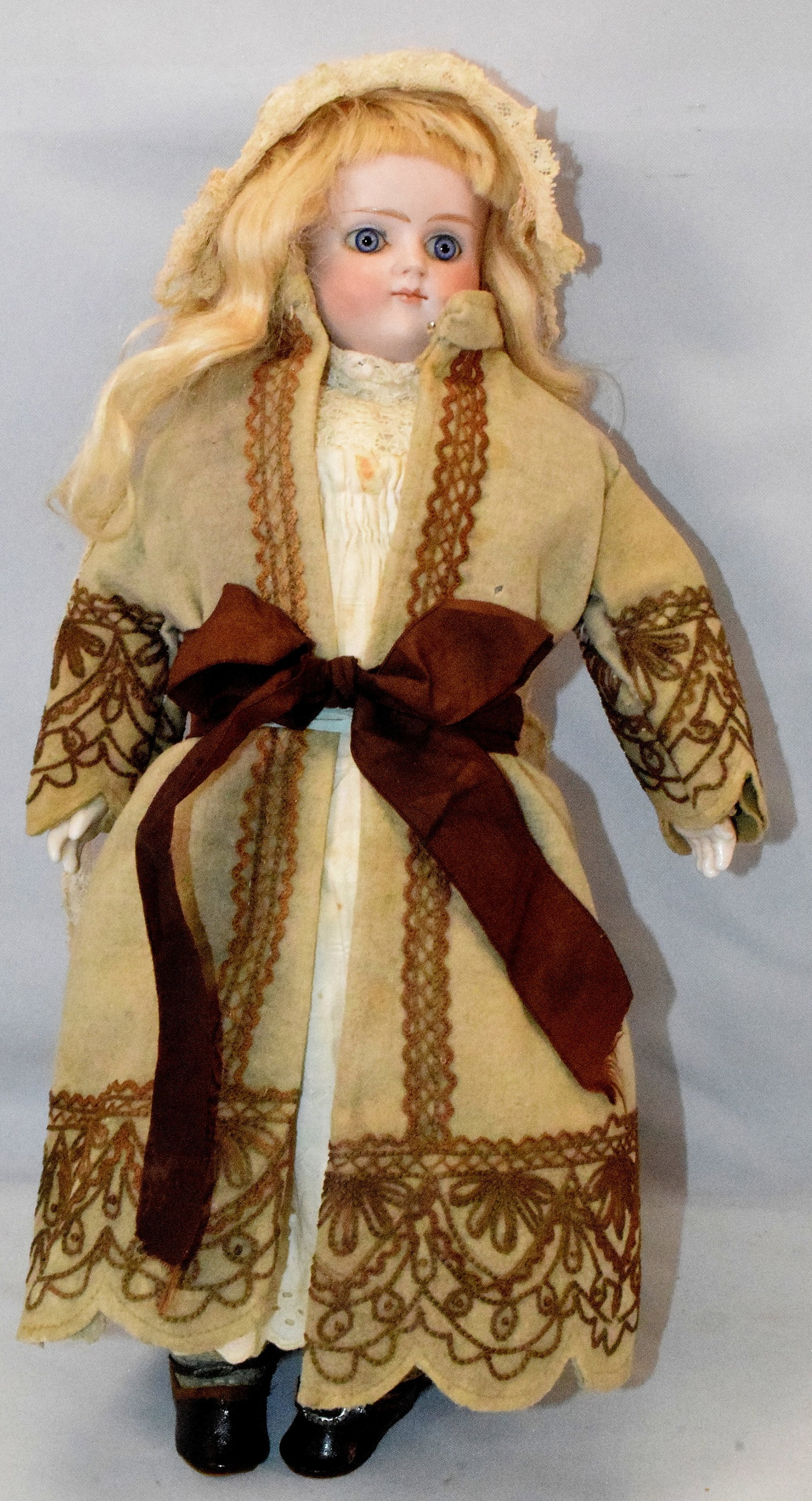 ANTIQUE PORCELAIN DOLL FIXED EYES & CLOSED MOUTH: Antique doll maybe French. Fixed blue eyes with closed mouth. Hand painted features. No marking on back of head. Leather body. Blonde wig. Clothing seems original as well as shoes. Some moth damageand