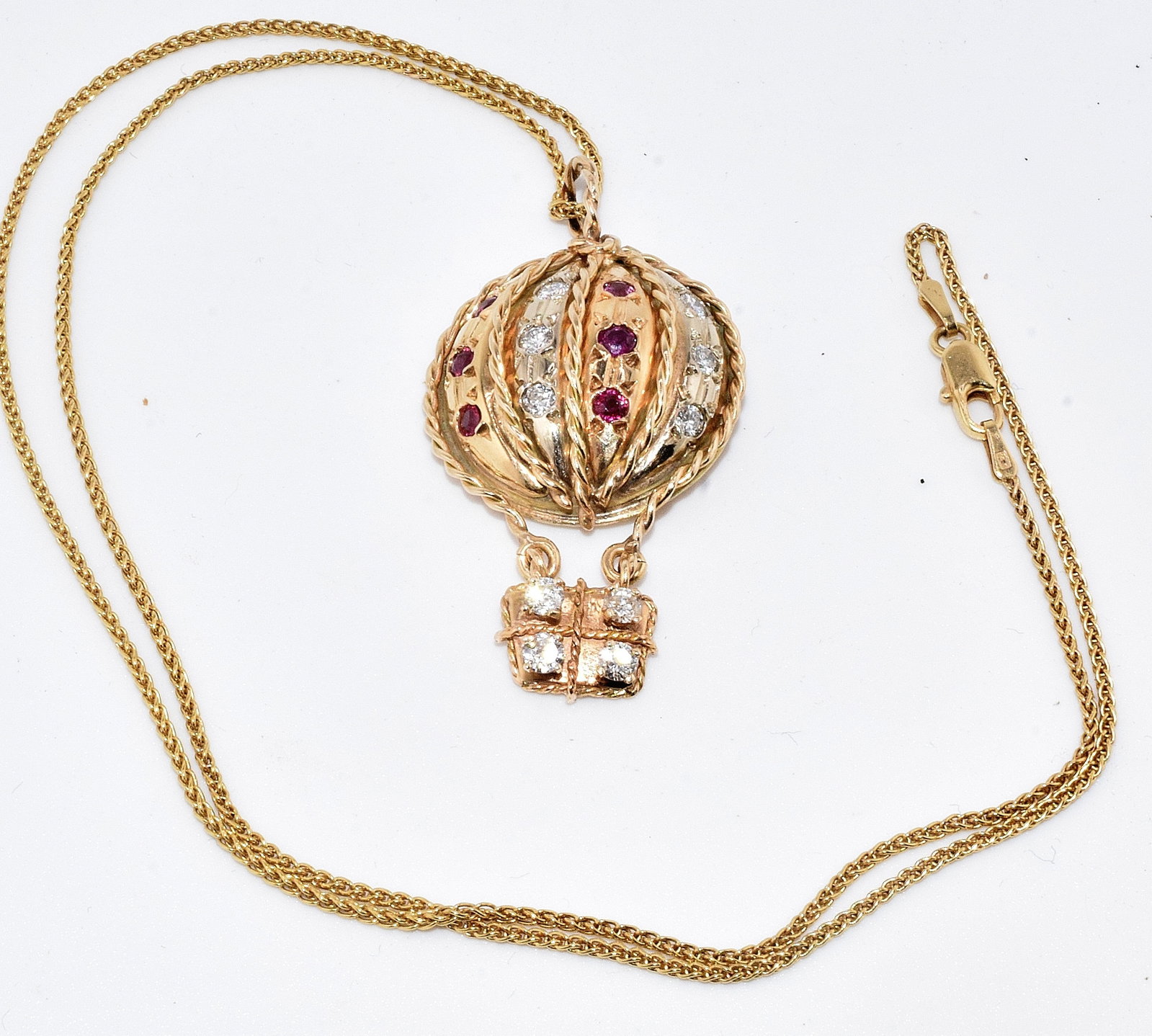 14K DIAMOND & RUBY BALLOON PENDANT & 14K NECKLACE: Fine 14k yellow gold pendant in the shape of a hotair balloon. Approx. 1 5/8 inches long with 10 white round prong set diamonds, each approx. 1/16 carat and 6 round rubies, each approx. 1/16 carat.