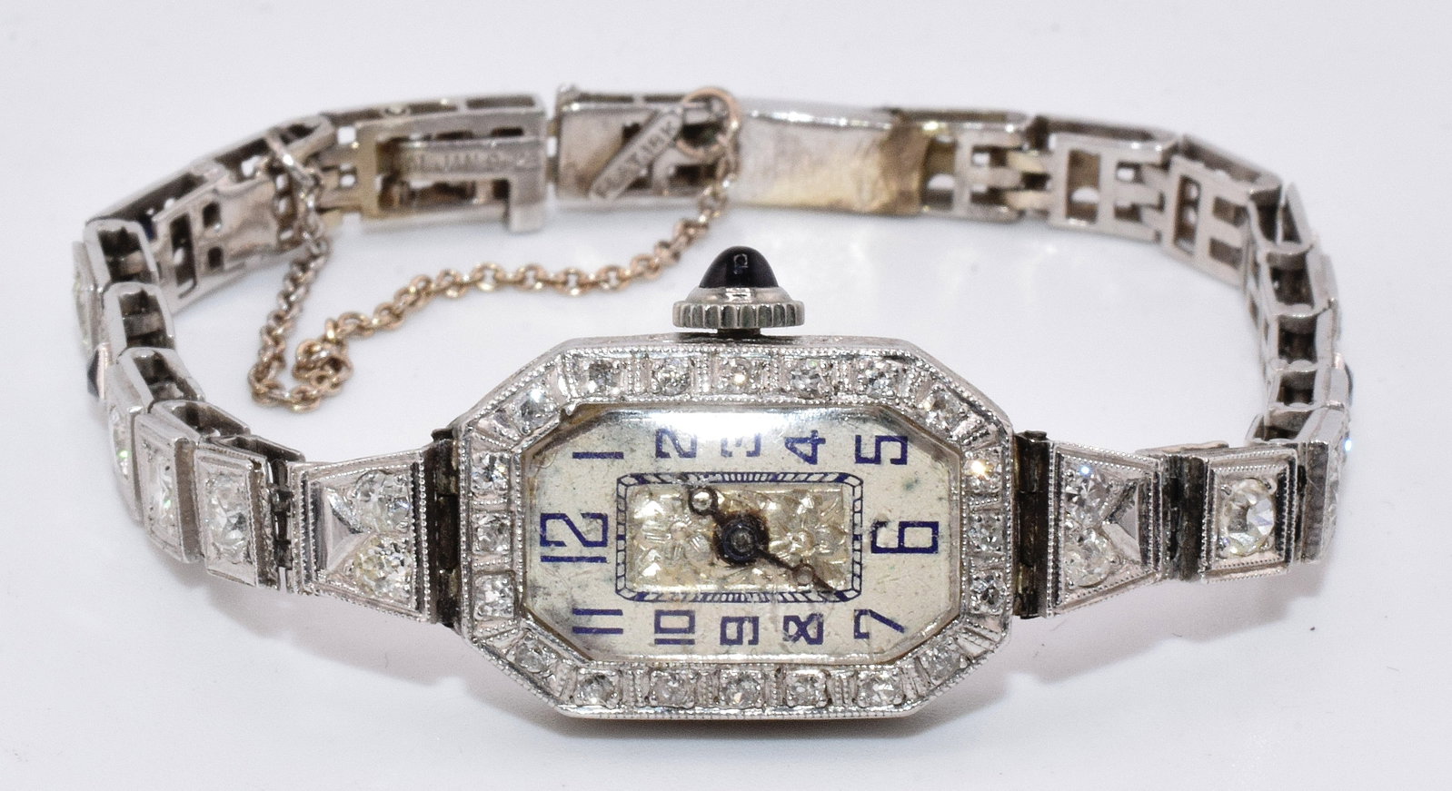LADY's 18K WHITE GOLD, DIAMOND & SAPPHIRE WATCH: Art Deco Lady's 18k wristwatch. Swiss movement. Rectangle case with 20 single white diamonds set inthe bezal. Blue sapphire cabochon crown, Crystral with a scratch. Bracelet-single linebracelet.