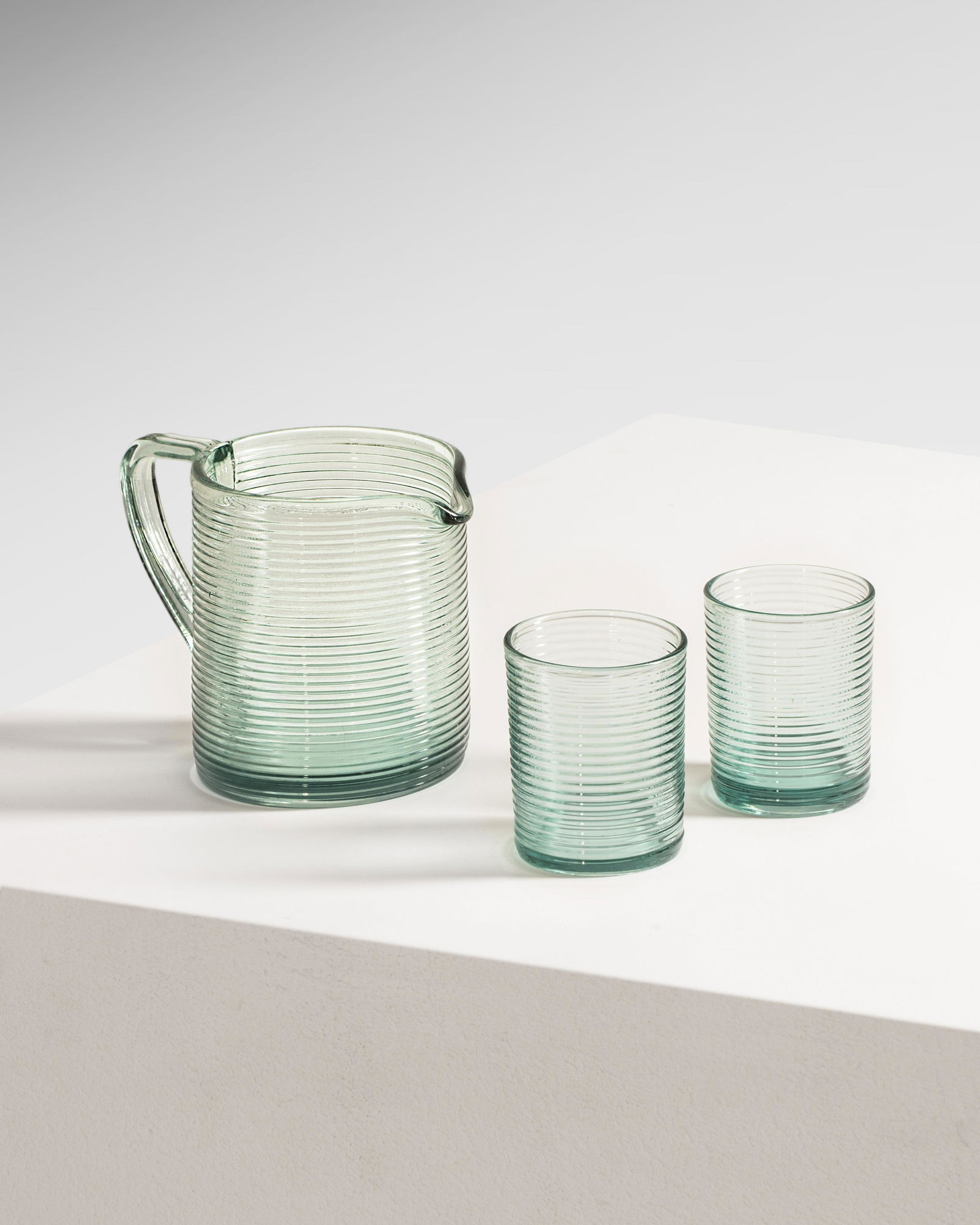 Aino Aalto: A pitcher and two glasses, designed by Aino Aalto in 1932 and manufactured by Iittala. Ensemble d'un pichet et deux verres, crÃ©Ã©s par Aino Aalto . Glass - Verre. Pitcher diam. 12,5cm height 14cm
