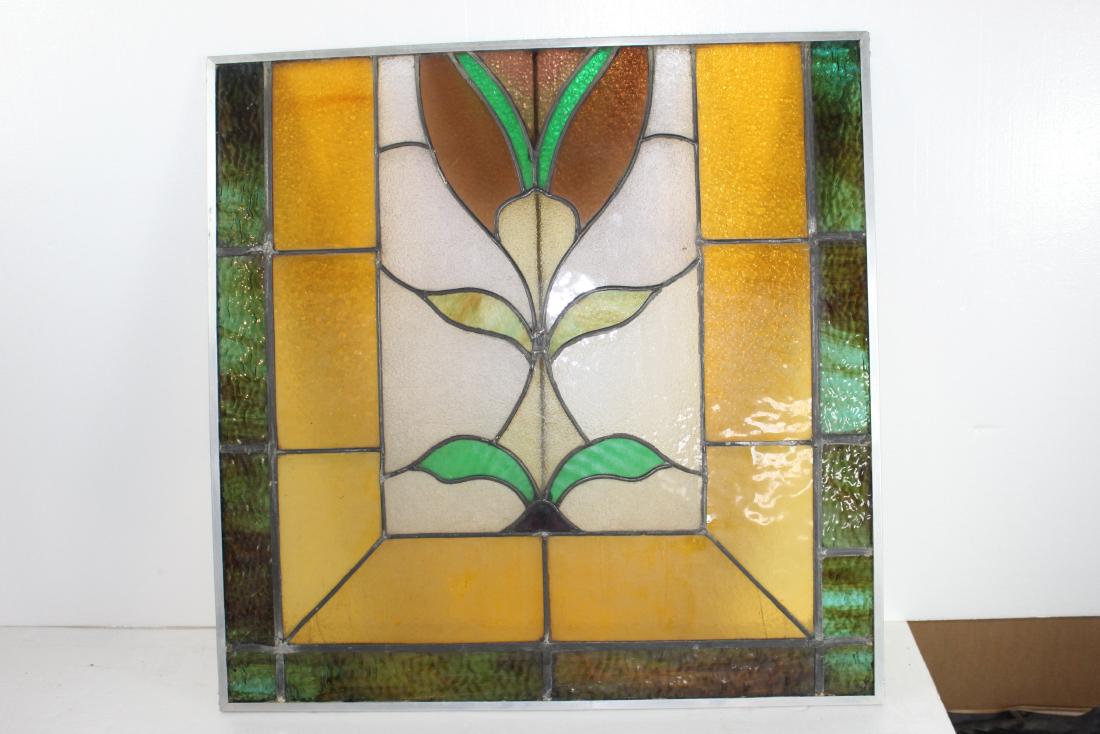 Old Lead Stained Glass Flower: This is a square shaped stained glass depicting an image of a flower. It is showing a symmetrical tulip whose colors are green, yellow and brown. It measures to 26â€™â€™ 