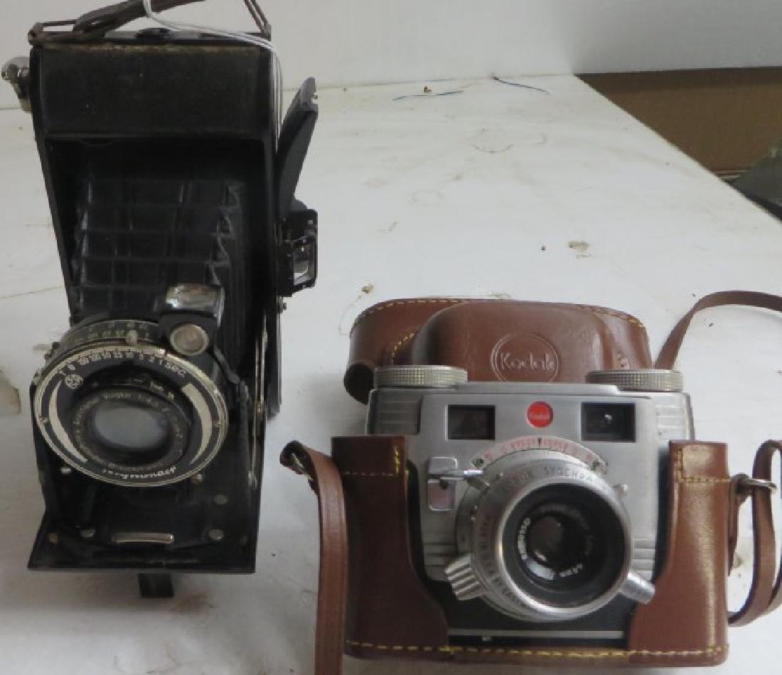 Lot of 2 Vintage Cameras: The first camera is Voigtlander Anastigmat Skopar 1:4.5 F- 11.4cm. no. 322660, with a stand on the bottom. 6 1/4â€™â€™ x 8â€™â€™ x 3 1/2