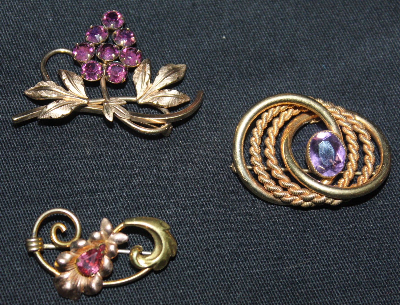(3) V.D. , Van Dell 1/20 12kt G.F. Brooches 21 grams: These 3 V.D. , Van Dell 1/20 12kt G.F. Brooches are in good condition, (1) Tri-circular Brooch w a purple stone 1 1/4" x 1", (2) Floral Brooch with a pink gem stone 1 1/4" x 1/2", Grape brooch with pu