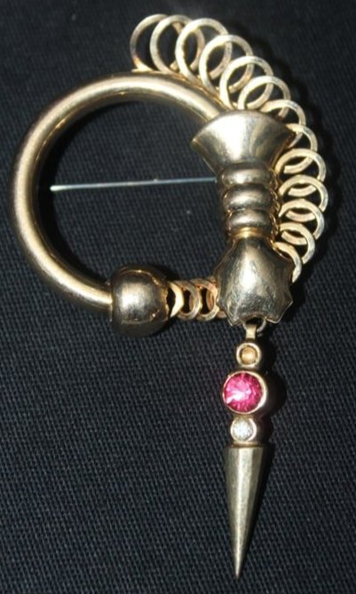 Regel 1/20 12kt Brooch 10 grams: Regel 1/20 12kt Brooch. This is a beautiful brooch, its circular with an abstract design, it has a dangle with a dark pink and clear stone . it is in good condition, it measures 1 1/4" x 3". The brooc