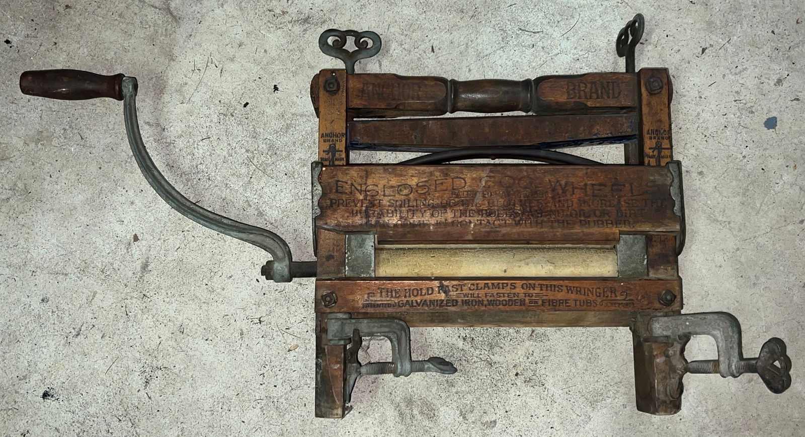 Vintage Anchor Brand Laundry Wringer: This vintage Anchor Brand laundry wringer is a manually operated machine used to squeeze water out of clothing after washing. Made from metal and wood, it extracts the water, making it easier to dry.