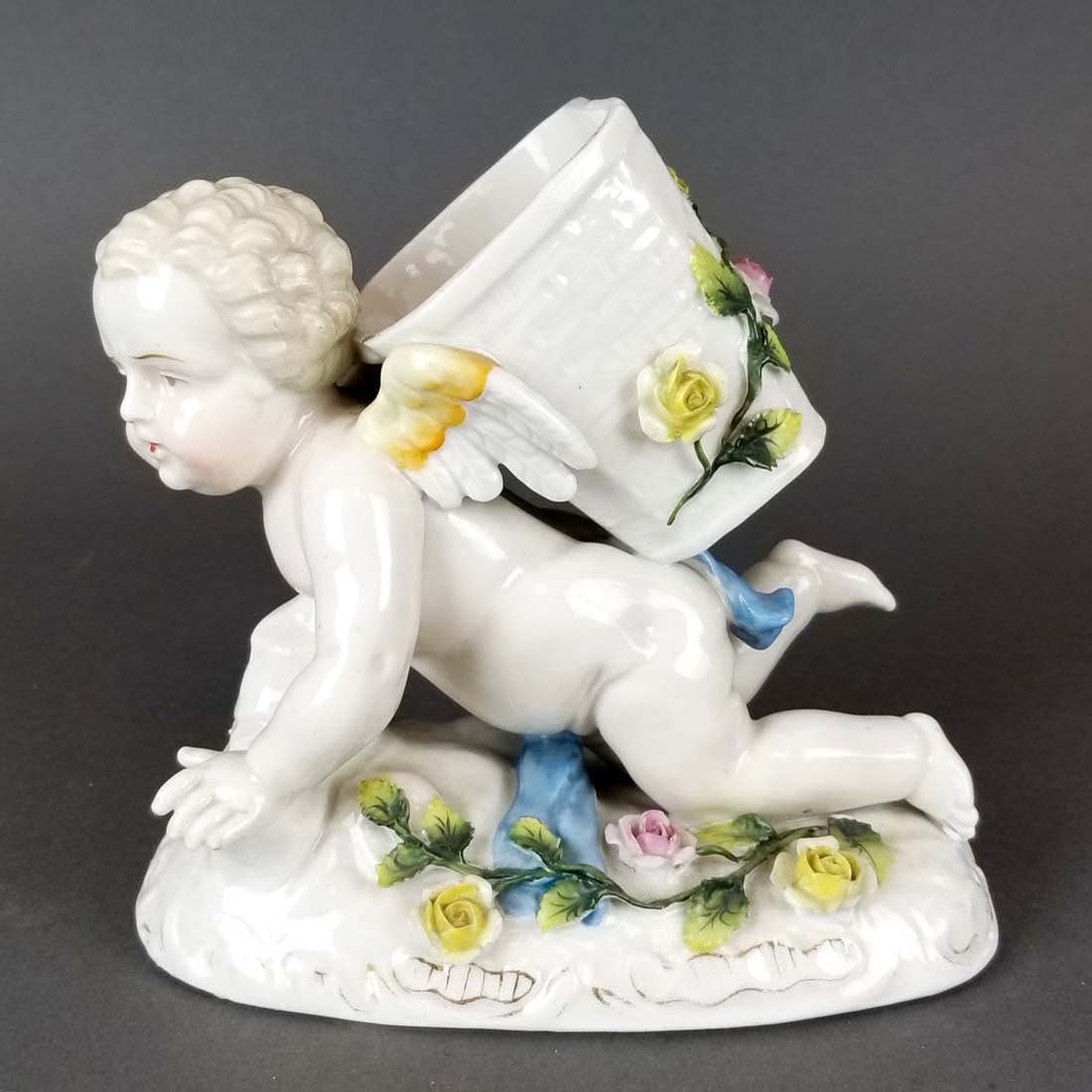 German Porcelain Figure of Cherub: German Porcelain Figure of Cherub. Measures H: 6" W: 6 1/2"