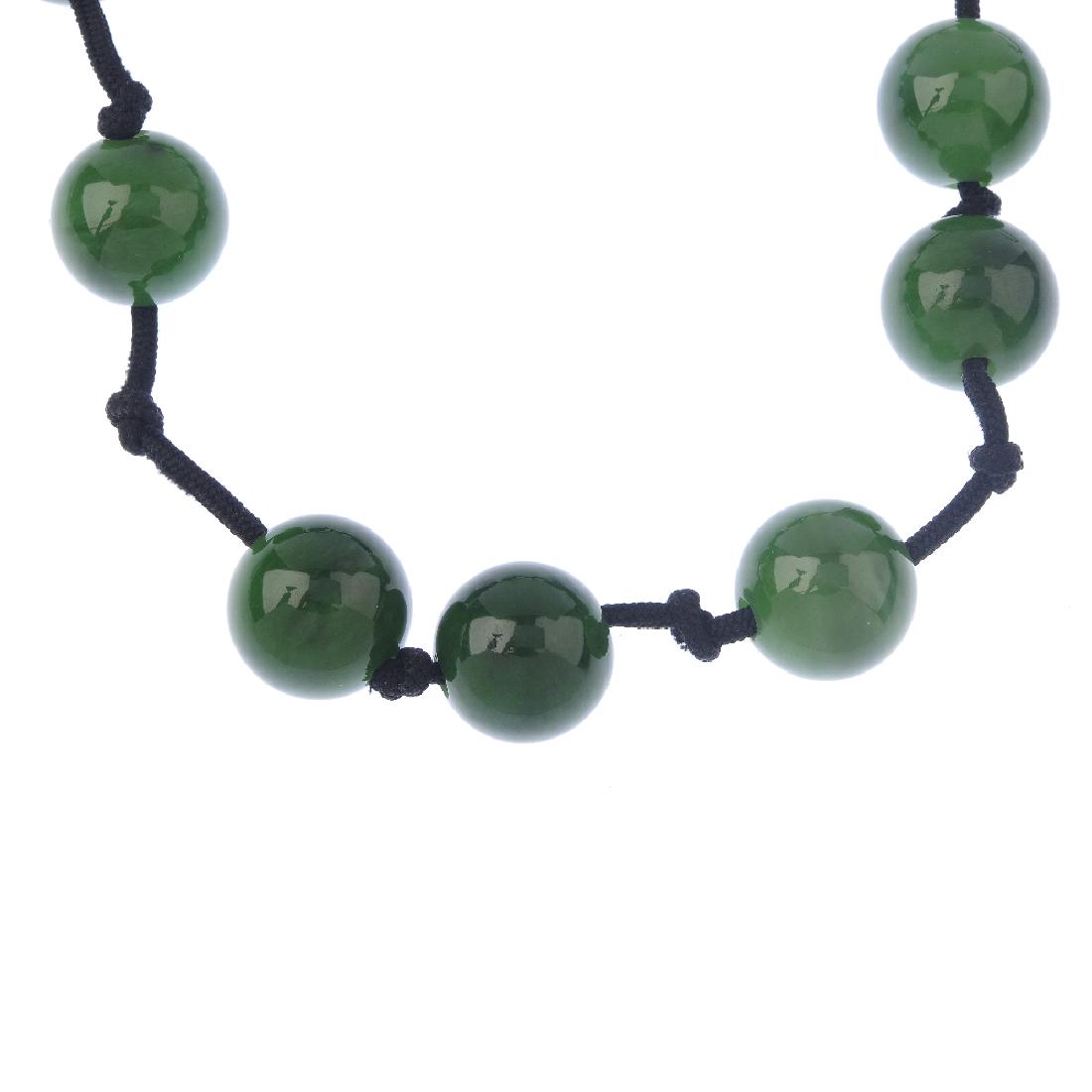 TIFFANY & CO. - a jade 'Sphere' necklace. Comprising: TIFFANY & CO. - a jade 'Sphere' necklace. Comprising twelve jade spheres, spaced along a black cord, with slide clasp. AF. Signed Tiffany & Co, Elsa Peretti, Hong Kong. With pouch and case. Jade untes