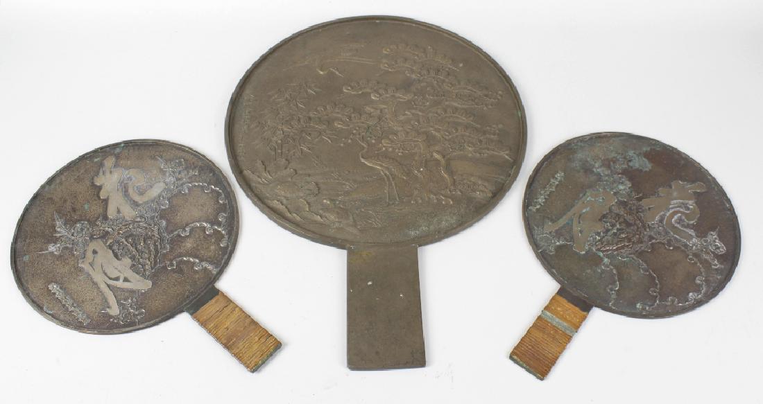 Three Japanese bronze mirrors. Each of circular form: Three Japanese bronze mirrors. Each of circular form with handle. the largest cast with cranes in a landscape, nine-character mark to centre left, 13.25 diameter x 18 long overall, (33.5cm x 46cm), th