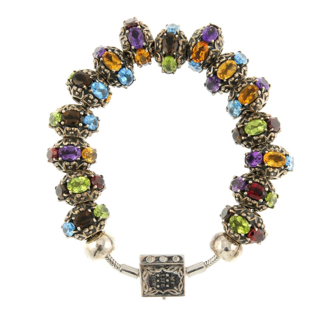 Two Storywheels charm bracelets. Both with snake-chain: Two Storywheels charm bracelets. Both with snake-chain bracelets to a book shape clasp, one with fifteen matching multi-gem charms and the other with thirteen mixed charms. Lengths 17.5 and 20cms. Wei