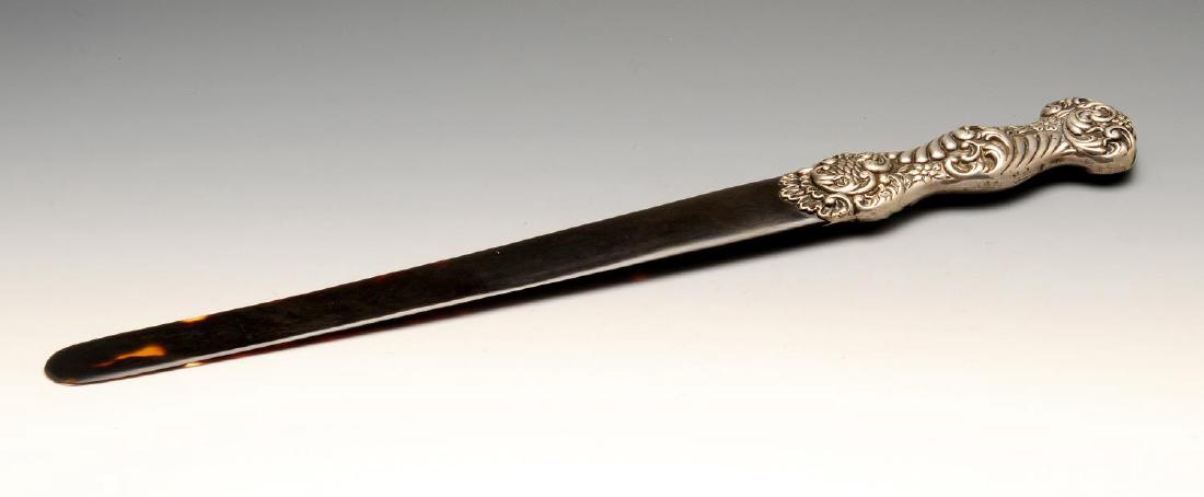 An Edwardian silver mounted tortoiseshell page turner,: An Edwardian silver mounted tortoiseshell page turner, the shaped handle embossed with floral scrolls. Hallmarked Birmingham 1901 with the maker's mark EB. Length measuring 16 inches (41 cm).