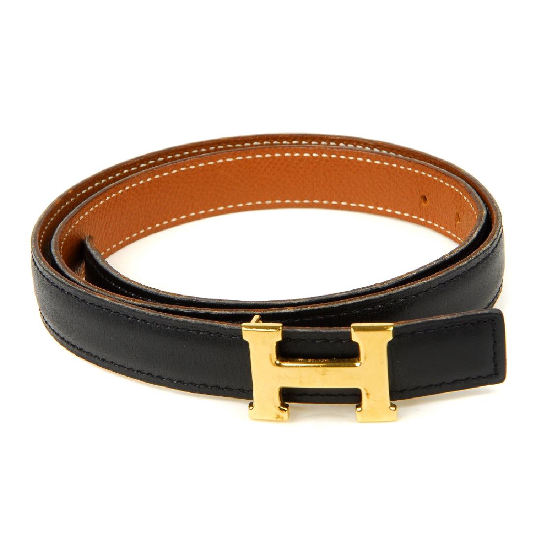 HERMÈS - a mini reversible logo buckle belt. Designed: HERMÈS - a mini reversible logo buckle belt. Designed with smooth black calfskin leather to one side and grained tan leather to the other, featuring maker's mini gold-tone detachable 'H' buckle faste