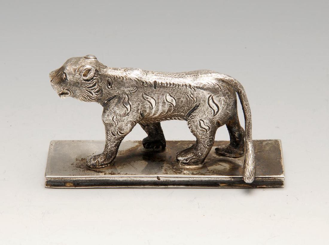 A white metal figure, modelled as an Indian tiger upon: A white metal figure, modelled as an Indian tiger upon an oblong base, previously mounted. Appears unmarked. Width of base measures 3 1/2 inches (9 cm), weight 5.8 ozt (183.2 grams).