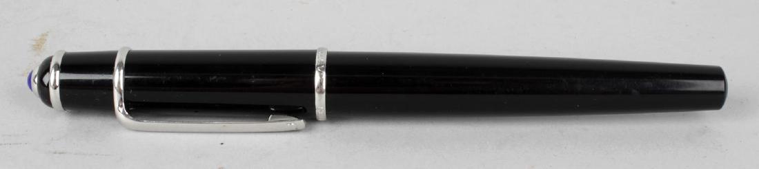 A Cartier Diablo ballpoint pen. The black laque de: A Cartier Diablo ballpoint pen. The black laque de chine body with blue paste cabochon to the screw-off cap, numbered 288484, 5.5,(14cm) long.