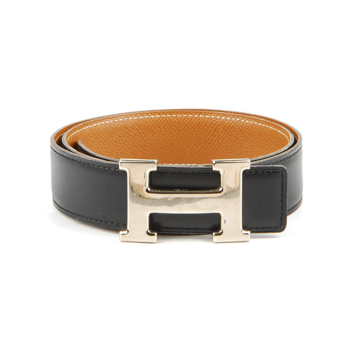 HERMÈS - a reversible logo buckle belt. Designed with: HERMÈS - a reversible logo buckle belt. Designed with smooth black leather to one side and grained tan leather to the other, featuring maker's reversible classic silver-tone 'H' buckle. Length measur