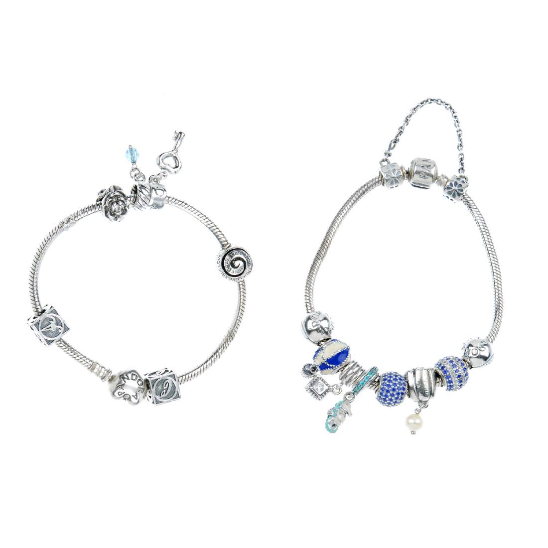 PANDORA - two charm bracelets. One with a barrel-shape: PANDORA - two charm bracelets. One with a barrel-shape clasp, the other with a heart-shape clasp, with a total of six Pandora charms, including an enamel hot air balloon charm, two spacers and a safet