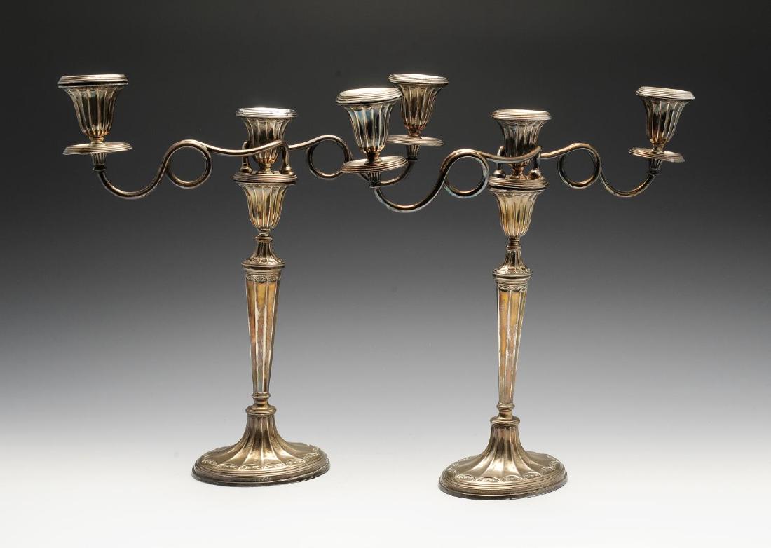 A pair of early twentieth century silver mounted: A pair of early twentieth century silver mounted candelabra, each with oval weighted base rising to a tapered column and vase shape socket, the removable upper section having twin looped branches lead