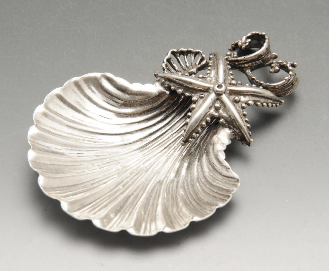 An Italian novelty silver caddy spoon, realistically: An Italian novelty silver caddy spoon, realistically modelled as a scallop shell with an applied starfish, pierced shell and seaweed terminal, marked 800 alongside the national mark for Arezzo (1944 -