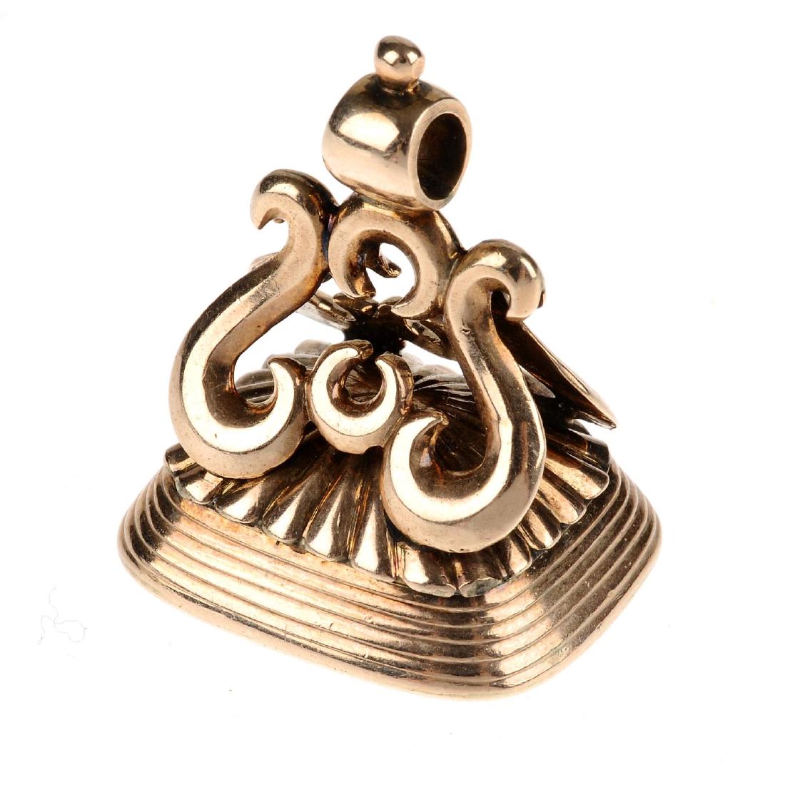 A carved carnelian fob. The rectangular carnelian with: A carved carnelian fob. The rectangular carnelian with intaglio engraved shield with stags heads over, to the scrollwork pedestal. Length 3.3cms. Weight 20.2gms.