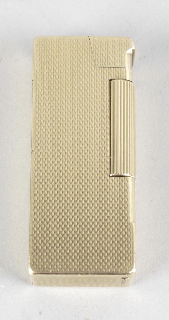 A Dunhill 9ct gold cigarette lighter, the body of: A Dunhill 9ct gold cigarette lighter, the body of oblong form with engine turned 'woven' effect decoration to the whole, the base hallmarked Birmingham 1949, 2.25 (5.5cm) long.