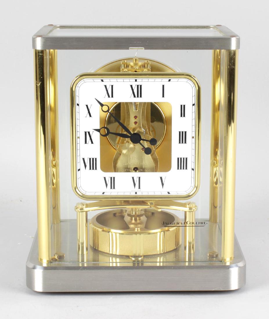 A Jaeger LeCoultre 540 Atmos clock, No 611978, the: A Jaeger LeCoultre 540 Atmos clock, No 611978, the square shaped chapter ring with Roman numerals framing exposed movement over bubble level, the bi metal framed case with removable glazed front panel