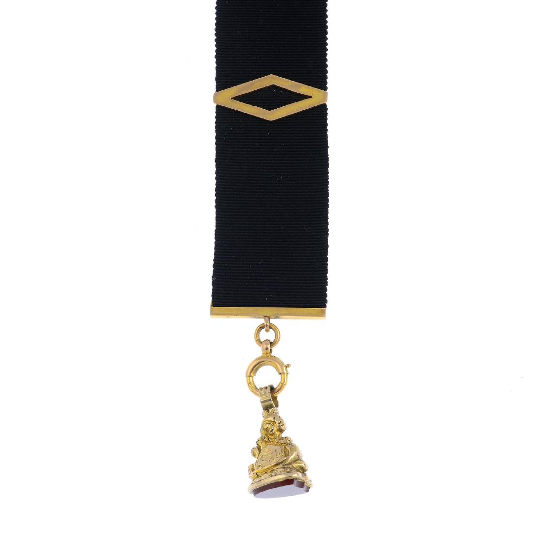 A carnelian fob, with an early 20th century 9ct gold: A carnelian fob, with an early 20th century 9ct gold moire Albertina. The shield-shape carnelian, with scrolling foliate pedestal, suspended from a moire Albertina with geometric slider. Length 17.5cm