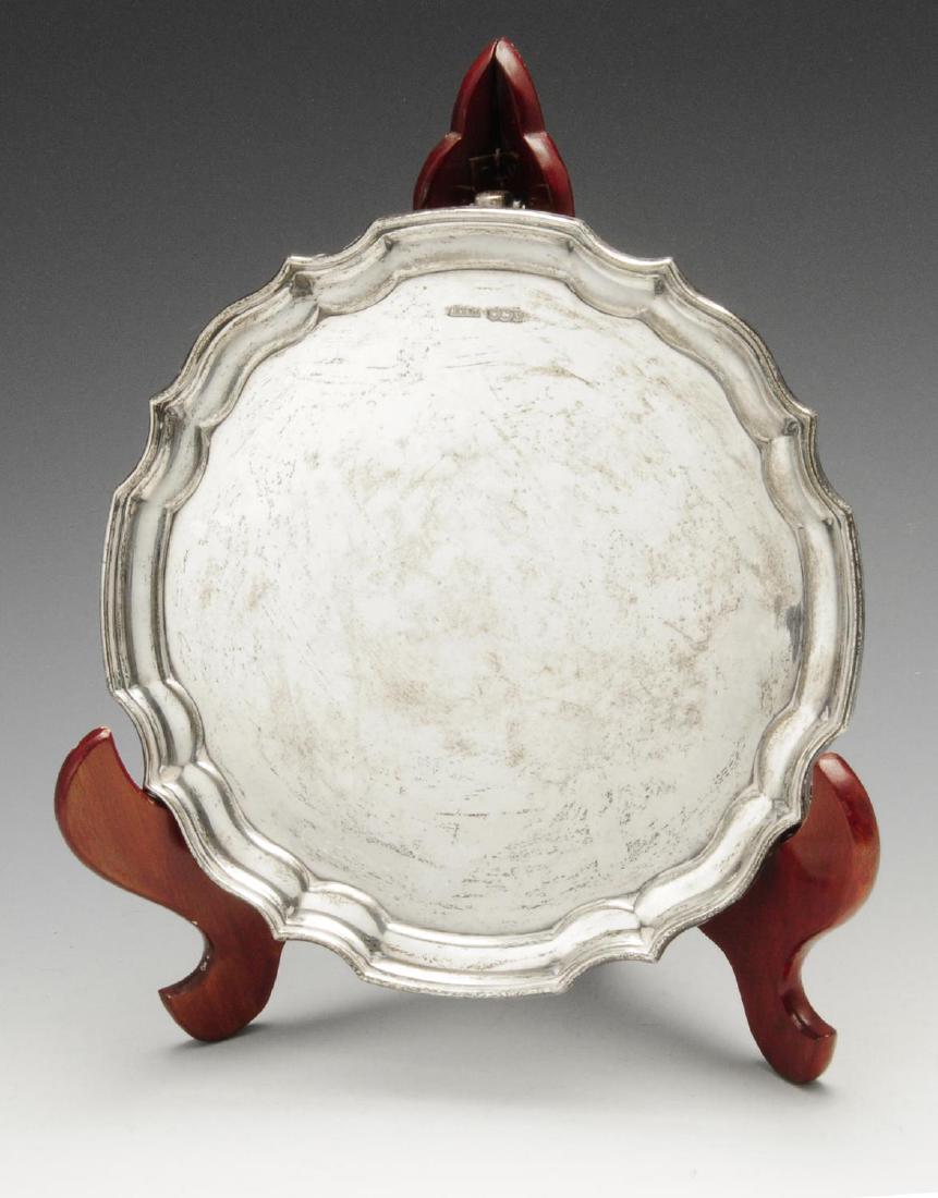 A 1930's small silver salver, of plain circular form: A 1930's small silver salver, of plain circular form with scalloped edge border and raised upon three scroll feet. Hallmarked Harrison Fisher & Co., Sheffield 1938. Diameter measures 8 1/8 inches (20.