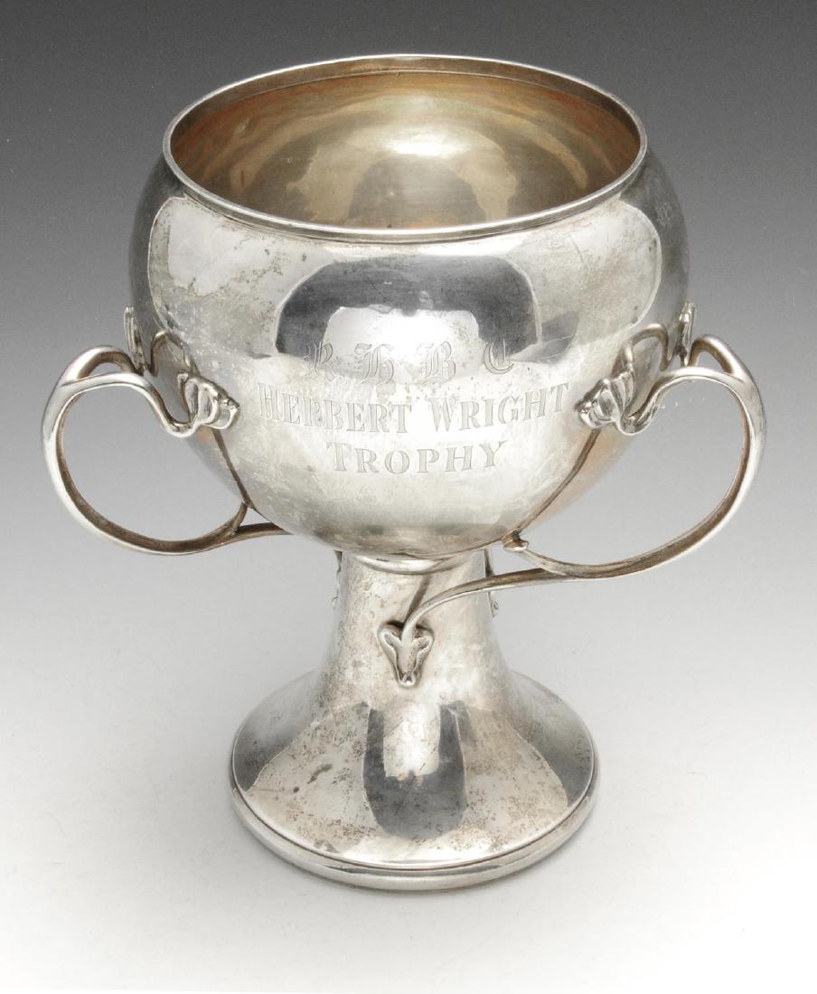 An Edwardian Art Nouveau silver tyg, the circular: An Edwardian Art Nouveau silver tyg, the circular bulbous bowl with trophy engraving to one side and applied with three sinuous tendril handles having stylised foliate terminals and leading to the fla