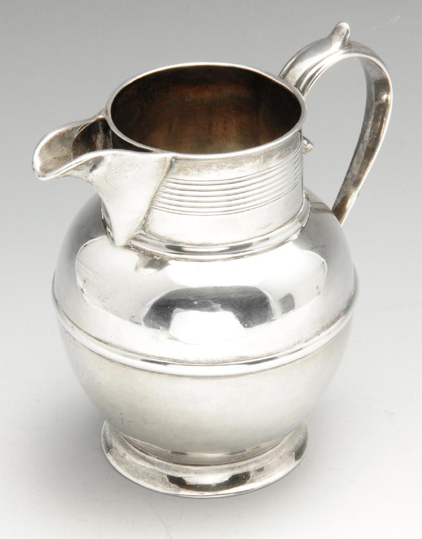 A George III small silver pitcher jug, of circular: A George III small silver pitcher jug, of circular bellied form with reeded scroll capped handle, further reeded decoration beneath the rim and raised upon a circular spread base. Hallmarked London 18
