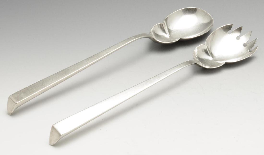 A pair of Edwardian silver salad servers, of oval: A pair of Edwardian silver salad servers, of oval pinched form with tapered angular stem and curved terminal. Hallmarked John Grinsell & Sons, Birmingham 1909. Length measuring 10 5/8 inches (27.3 cm)
