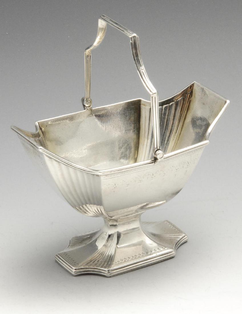A George III silver swing-handled sugar basket, of: A George III silver swing-handled sugar basket, of pedestal form with fluted corner detail, reeded rims and stipple engraved border decoration, the swing handle also reeded. Hallmarked William Plummer