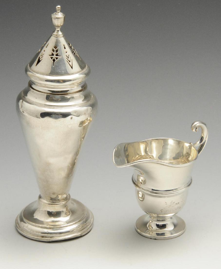A 1920's small silver cream jug, of helmet shaped form: A 1920's small silver cream jug, of helmet shaped form with high arch flying scroll handle and raised upon a circular splayed base, hallmarked Birmingham 1926, maker's mark partly distorted probably J