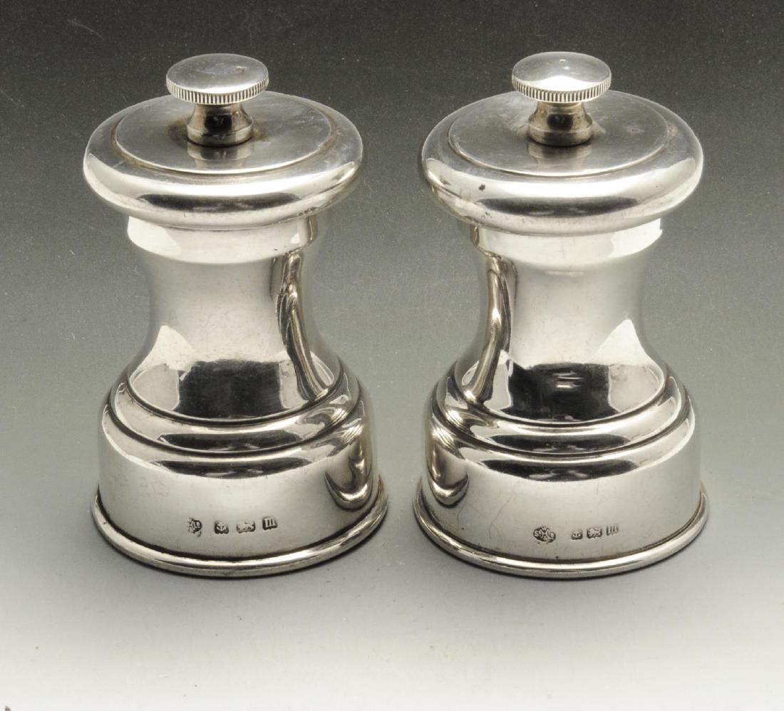 A small pair of early twentieth century silver mounted: A small pair of early twentieth century silver mounted pepper mills, each of plain circular waisted form with moulded base rim. Hallmarked William Hutton & Sons Ltd., Birmingham 1911. Height measuring