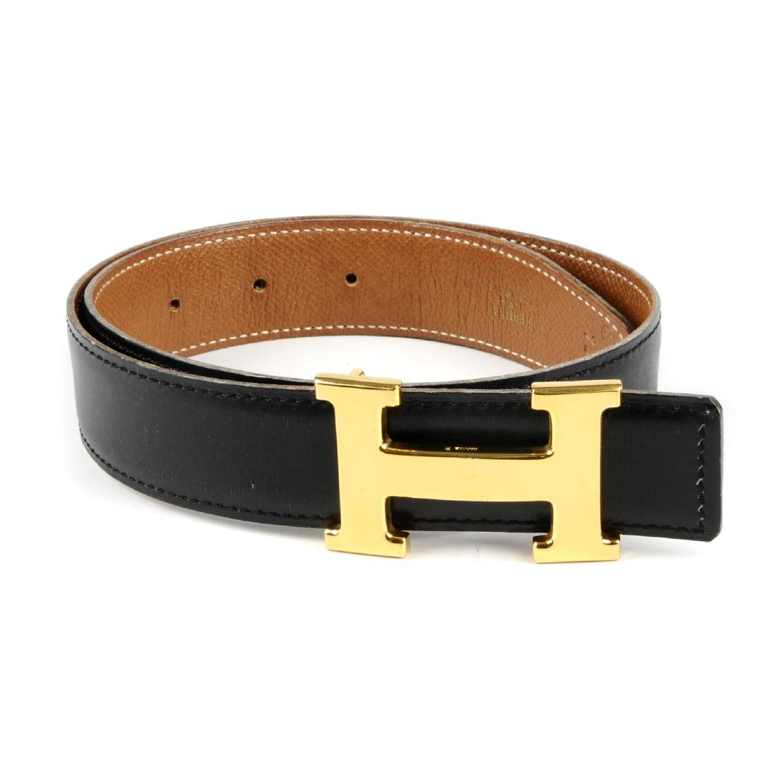 HERMÈS - a ladies reversible logo buckle belt. Designed: HERMÈS - a ladies reversible logo buckle belt. Designed with smooth black leather to one side and grained tan leather to the other, featuring maker's reversible classic gold-tone 'H' buckle. Stamped