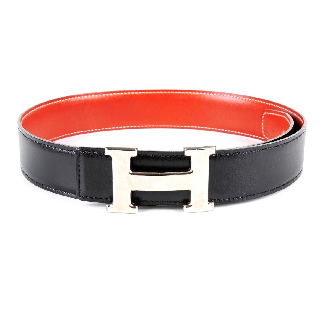 HERMÈS - a reversible logo buckle belt. Designed with: HERMÈS - a reversible logo buckle belt. Designed with smooth black leather to one side and smooth burnt orange leather to the other, featuring maker's reversible classic silver-tone 'H' buckle. Stamp