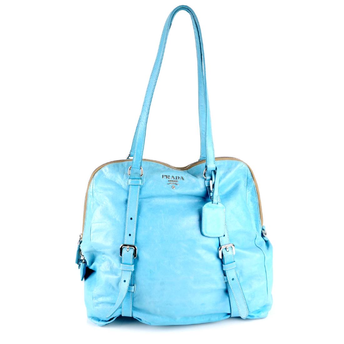 PRADA - a pale turquoise leather handbag. Featuring: PRADA - a pale turquoise leather handbag. Featuring wraparound strap and buckle details, silver-tone hardware, dual flat leather handles with detachable leather ID tag and a leather clochette with pad