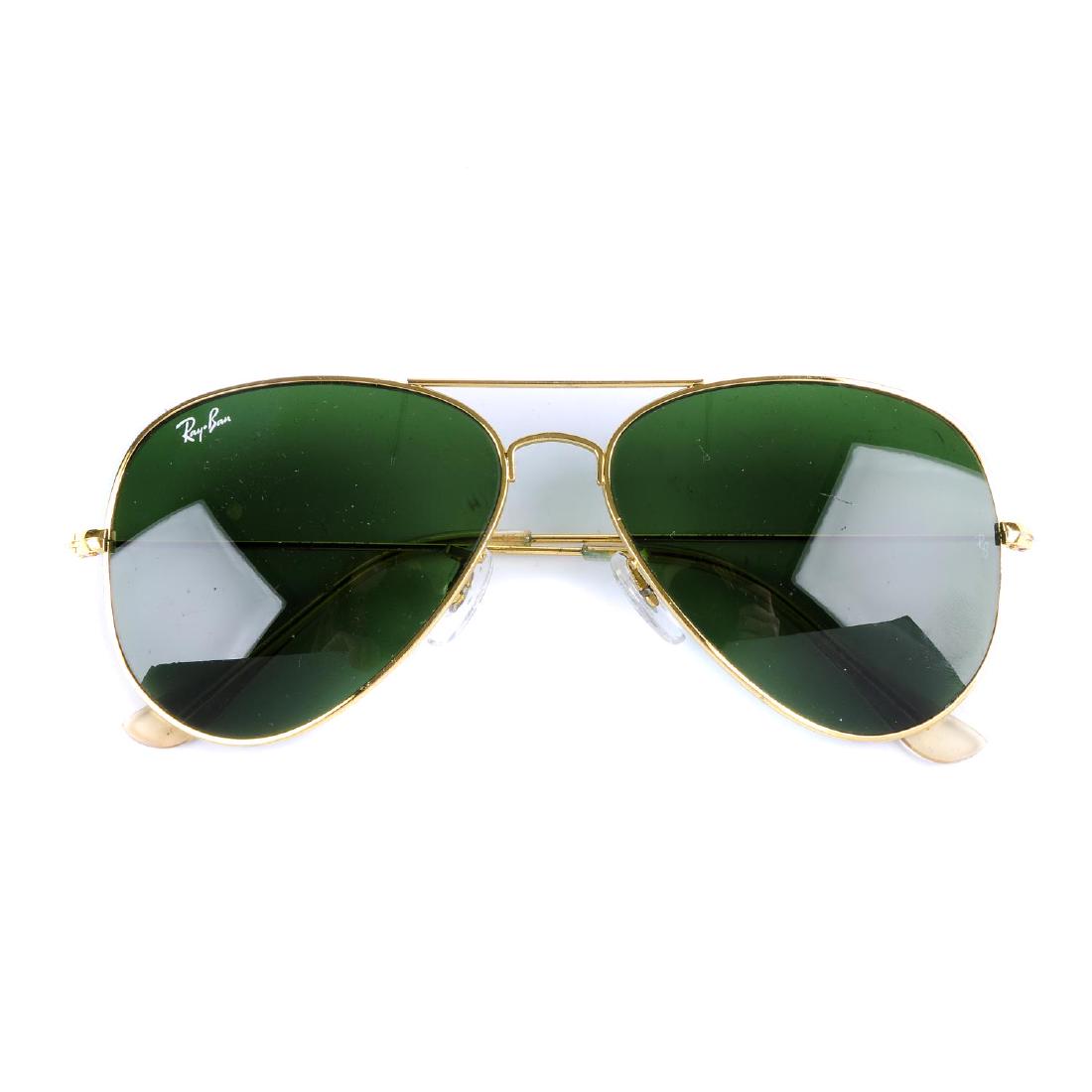 RAY BAN - a pair of Aviator sunglasses. Featuring dark: RAY BAN - a pair of Aviator sunglasses. Featuring dark green lenses of the classic rounded aviator design with thin gold-tone frames and clear earpieces. With maker's case.