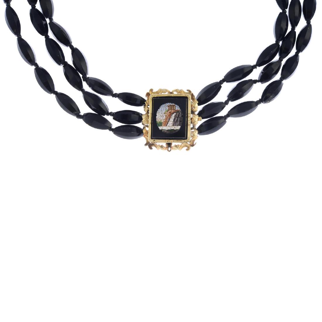 A glass bead three-row choker necklace. Comprising: A glass bead three-row choker necklace. Comprising three strands of faceted glass beads, to the late Victorian gold micro mosaic clasp. Length 38cms. Total weight 61.4gms.