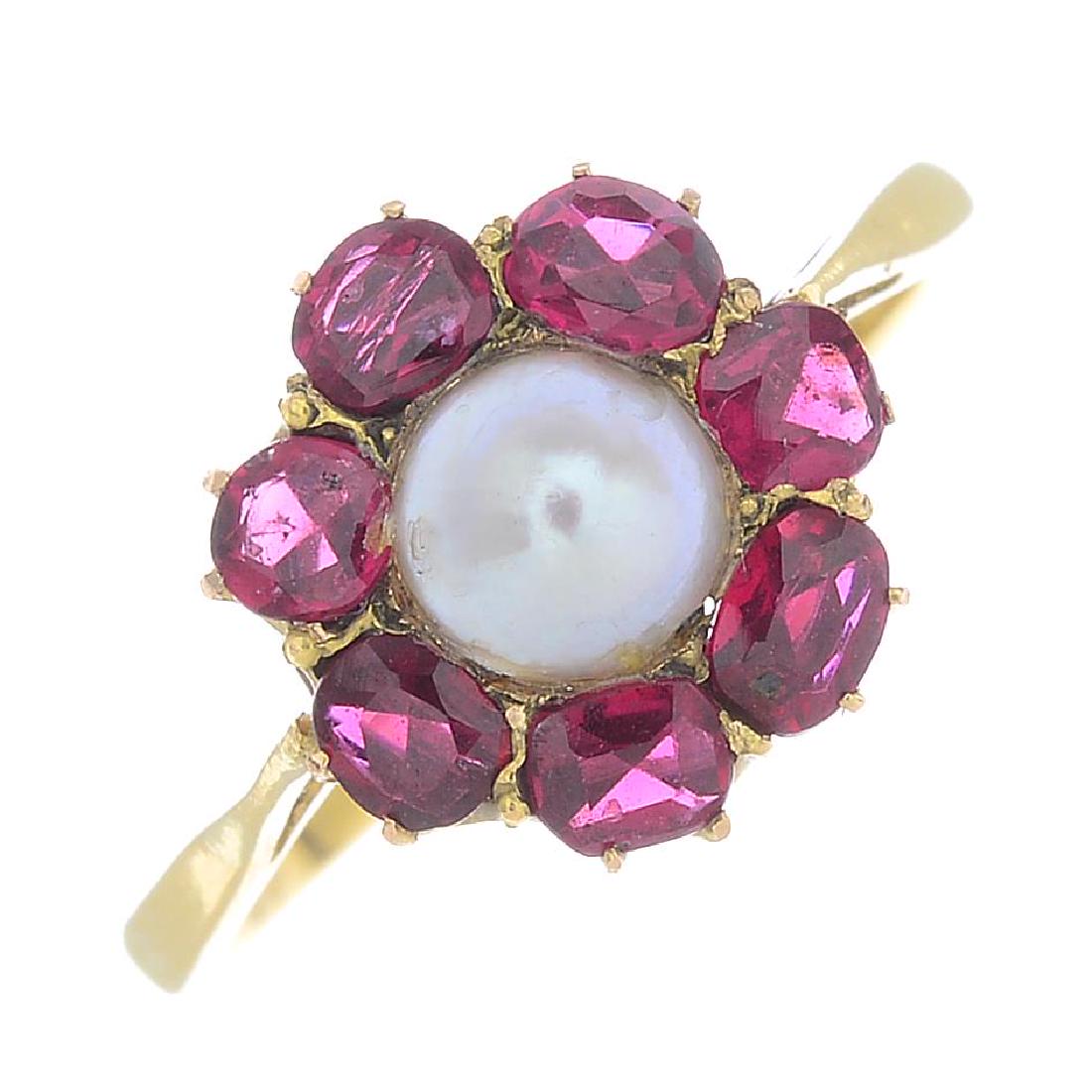 A ruby and cultured pearl cluster ring. The cultured: A ruby and cultured pearl cluster ring. The cultured pearl, with cushion-shape ruby surround, to the tapered shoulders and band. Total ruby weight 0.95ct. Ring size L1/2. Weight 3.3gms.