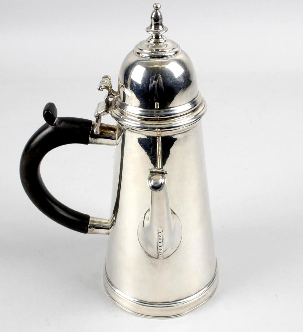 An Edwardian Britannia silver cafe-au-lait pot, the: An Edwardian Britannia silver cafe-au-lait pot, the plain tapered form with hinged and domed lid to a scroll thumb-piece and curved wood handle, the spout with hinged tip. Hallmarked Charles Stuart Ha