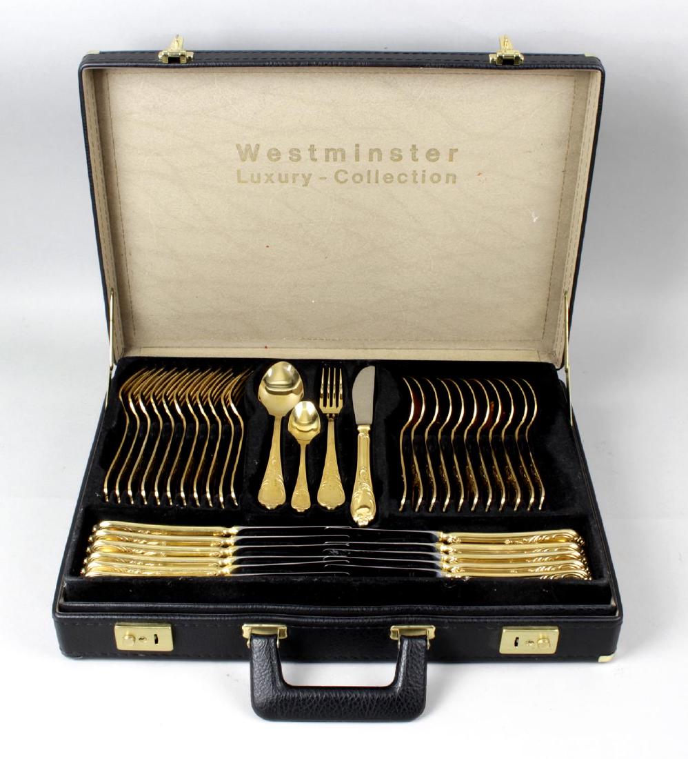 A modern German gold plated canteen for twelve place: A modern German gold plated canteen for twelve place settings by Solingen, comprising dinner knives and forks, dessert spoons, teaspoons, pastry forks and various serving utensils including ladles, a
