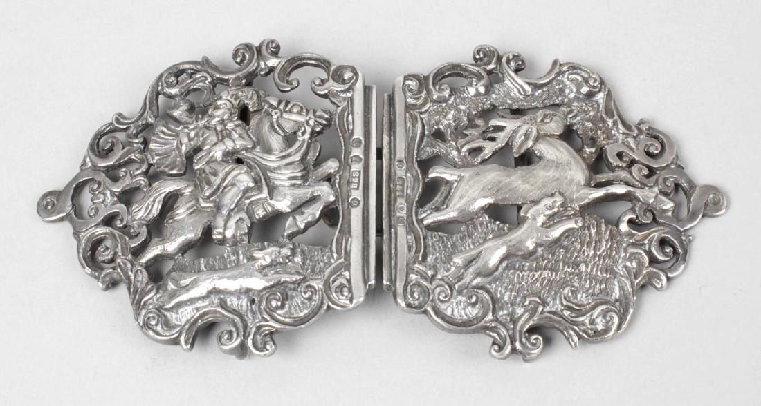 A late Victorian Scottish silver silver belt buckle, in: A late Victorian Scottish silver silver belt buckle, in two sections, decorated with a stag hunting scene within a pierced and scrolled surround. Hallmarked Brook & Son, Edinburgh 1895. Maximum length