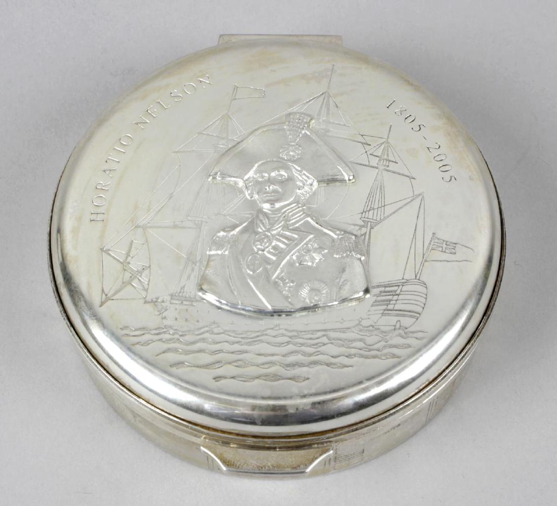 A modern limited edition silver circular box,: A modern limited edition silver circular box, commemorating Horatio Nelson and the Battle of Trafalgar, the hinged lid with relief portrait bust of Nelson against an engraved scene of HMS Victory at s