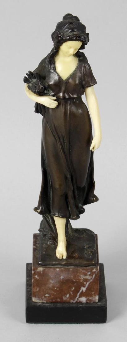 An Art Deco style bronze figure, modelled as a lady in: An Art Deco style bronze figure, modelled as a lady in flowing dress holding flowers, upon a rouge marble square base, 9.5 (23cm) high.
