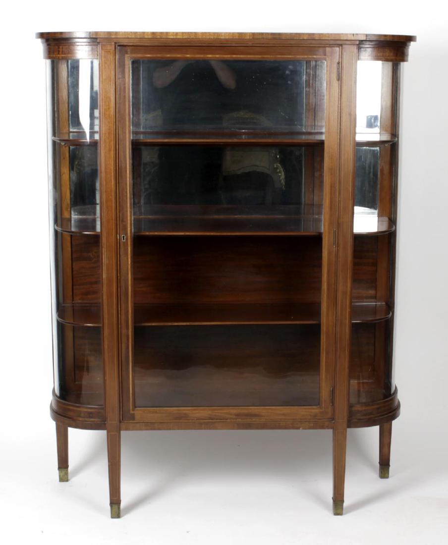 An early 20th century mahogany side cabinet, the: An early 20th century mahogany side cabinet, the projecting cornice above glazed bow sides and a central glazed door, the whole upon square tapered legs, 51.5 x 48 (131cm x 122cm).