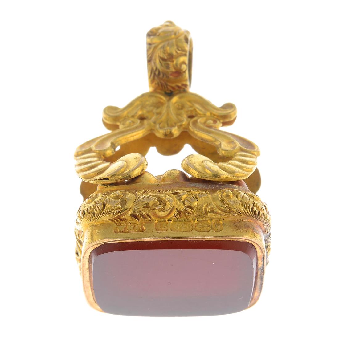 A late Victorian 15ct gold carnelian fob. The: A late Victorian 15ct gold carnelian fob. The rectangular-shape carnelian panel, within a foliate surround and scrolling pedestal. Hallmarks for Birmingham 1876. Length 3.6cms. Weight 15.9gms.