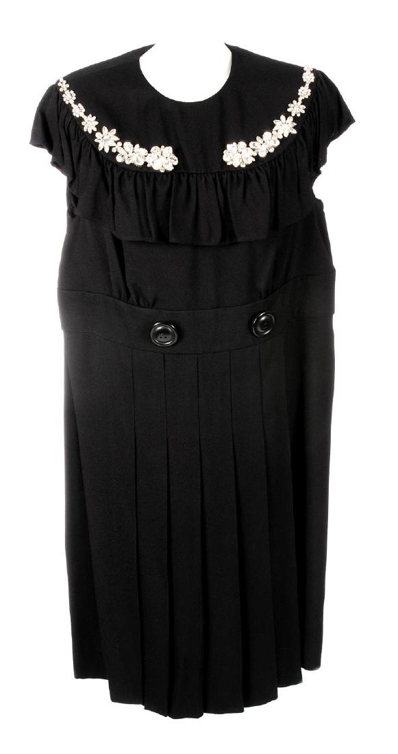 MIU MIU - a black embellished pleated dress. With a: MIU MIU - a black embellished pleated dress. With a bead embellished front ruffled bib, a pleated knee-length skirt and buttoned waist detailing. Labelled Miu Miu, size 50. With maker's coat hanger, d