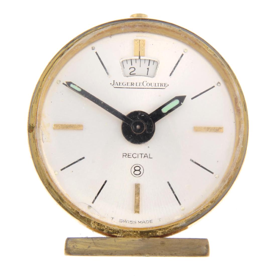 An alarm clock by Jaeger-LeCoultre. Gold plated case.: An alarm clock by Jaeger-LeCoultre. Gold plated case. Manual wind movement. Silvered dial. 46mm.