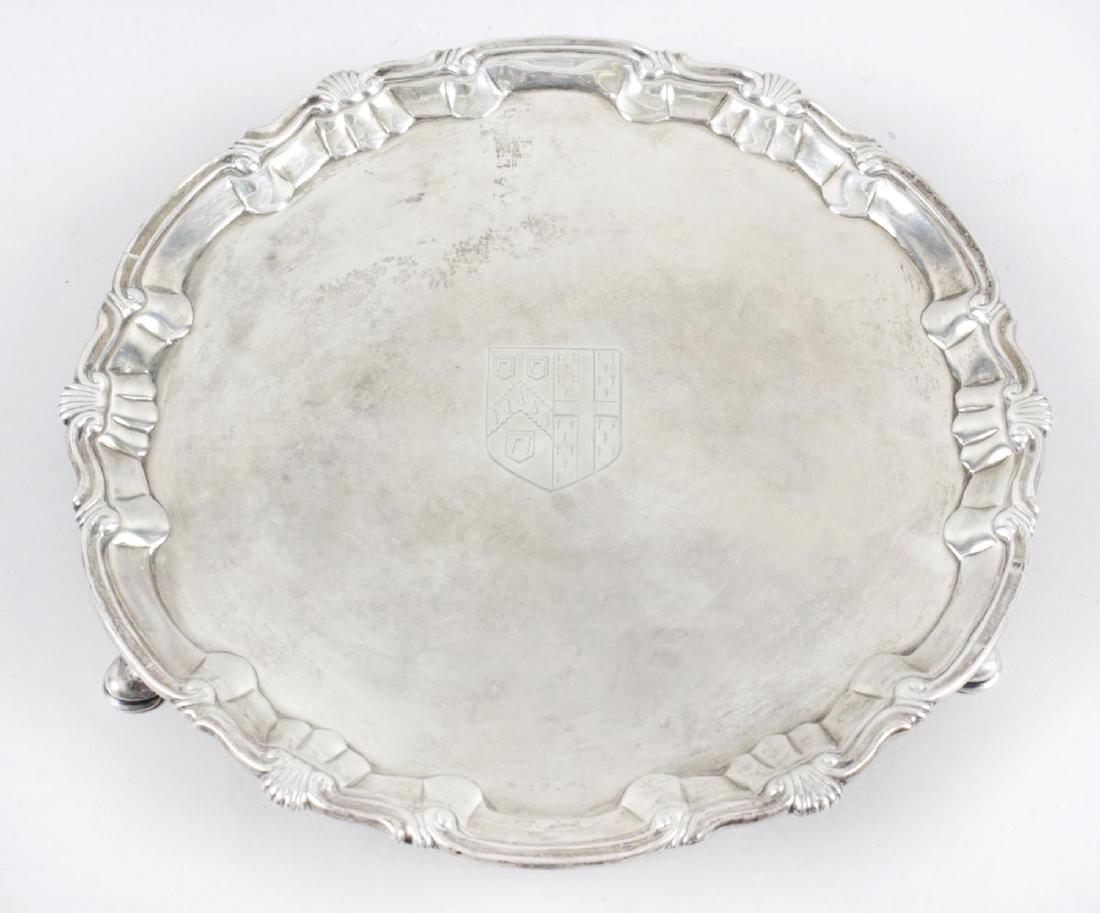 A George II small silver salver, the circular form with: A George II small silver salver, the circular form with scroll rim interspersed with shell motifs, engraved armorial to the plain centre and raised on three hoof feet. Hallmarked William & Robert Peas