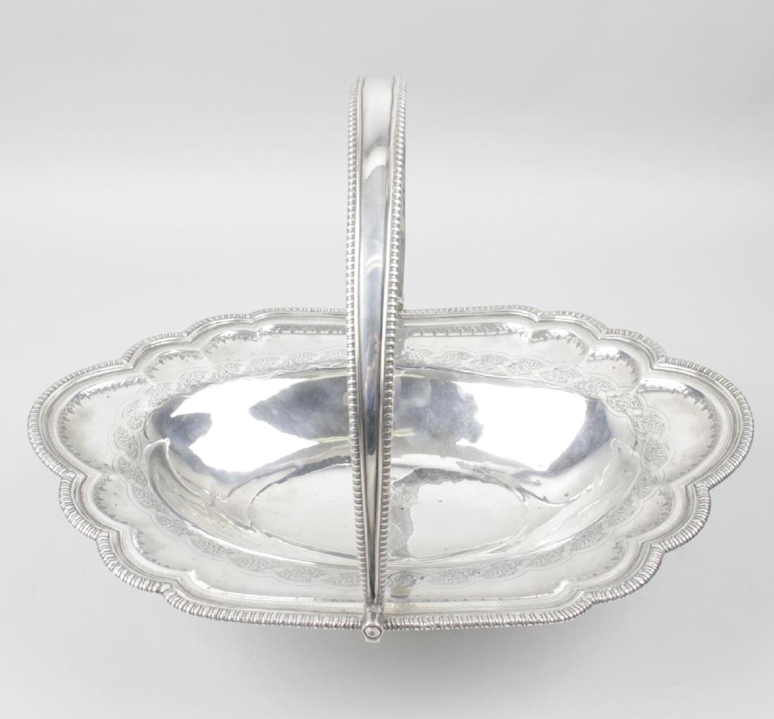 A George III silver swing handle basket by Peter, Ann &: A George III silver swing handle basket by Peter, Ann & William Bateman, the oval form with a scalloped and gadroon rim enclosing engraved foliate borders and a double crest engraving to the centre, d